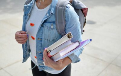 person wearing a jean jacket and holding books