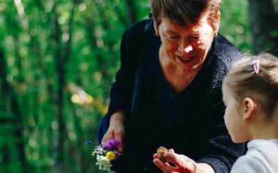 an older woman stooping to help a young child in the forest