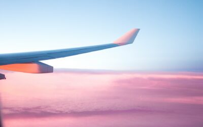 airplane wing over a blue sky and pink clouds